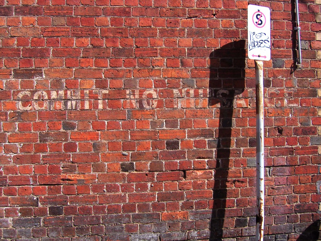 A brick wall with the words "commit no nuisance" on it