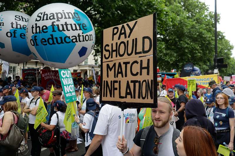 A man holding a placard that says "Pay Should Match Inflation" at a TUC rally