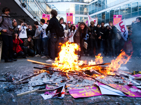 A group of student protestors gather around burning placards at Millbank Tower in 2010
