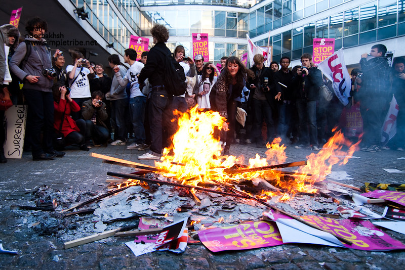 A group of student protestors gather around burning placards at Millbank Tower in 2010