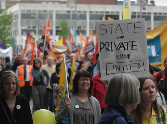 A person holding a placard that reads "State and Private Stand United" at a protest