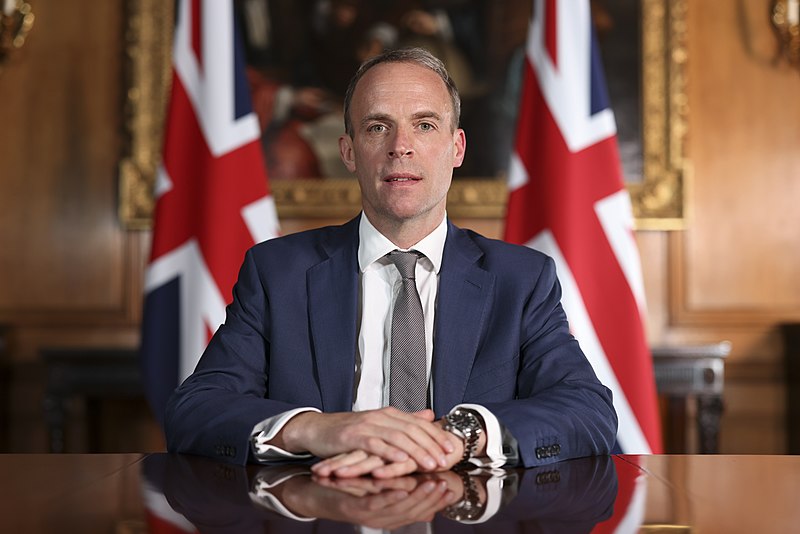 Dominic Raab sits in front of two union flags