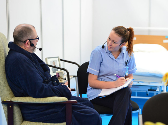 A man speaks with a nurse in a care setting