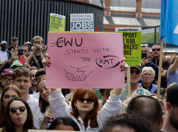 A woman at a rally holds a placard that reads "CWU stands with RMT"