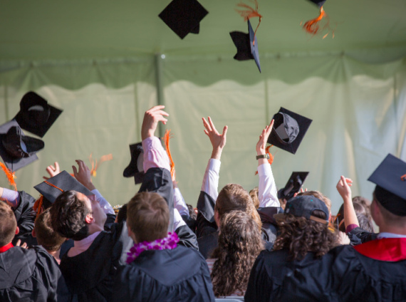 Students toss their motar boards in the air at a graduation ceremony