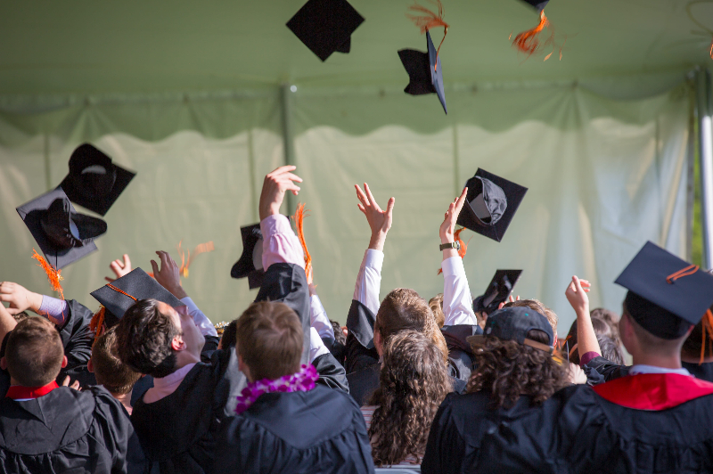 Students toss their motar boards in the air at a graduation ceremony