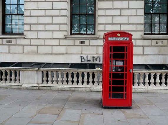 Black Lives Matter graffiti on a grey wall, with a red telephone box in the foreground