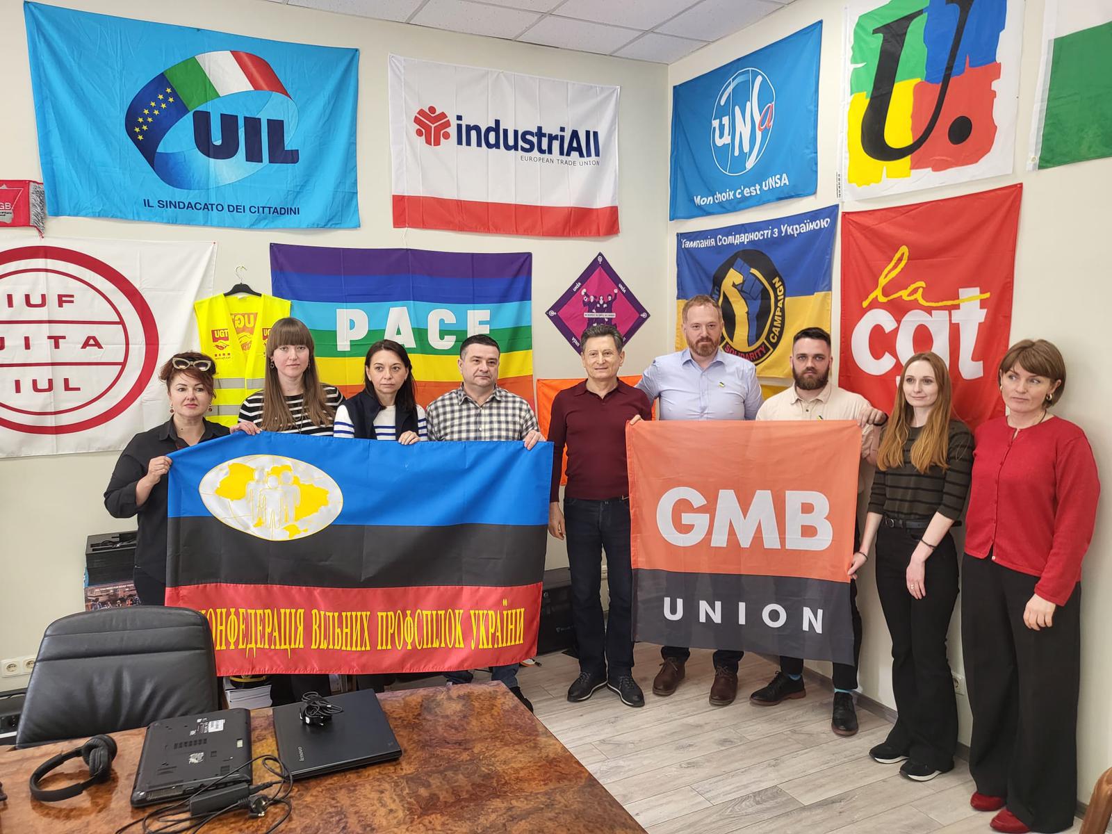 A GMB delegation and KVPU delegation hold respective banners in an office